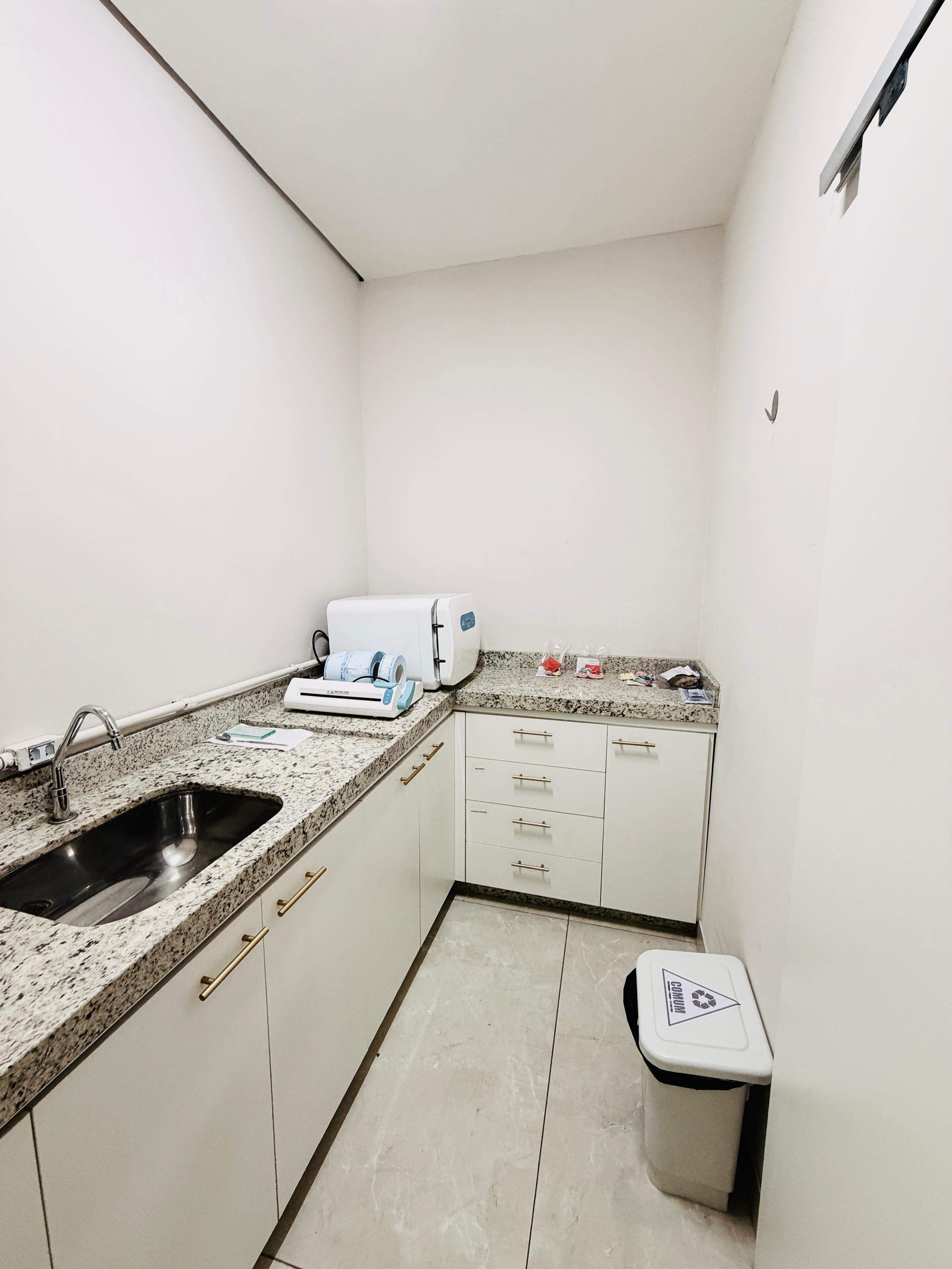 Sala de esterilização da Essence com autoclave, seladora de embalagens e pia sobre bancada de granito